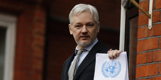 Julian Assange hält eine Papiere mit dem Logo der UN in die Kamera Julian Assange hält eine Papiere mit dem Logo der UN in die Kamera