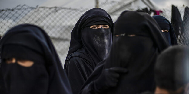 Frauen in Niqab stehen vor einem Maschendrahtzaun Frauen in Niqab stehen vor einem Maschendrahtzaun
