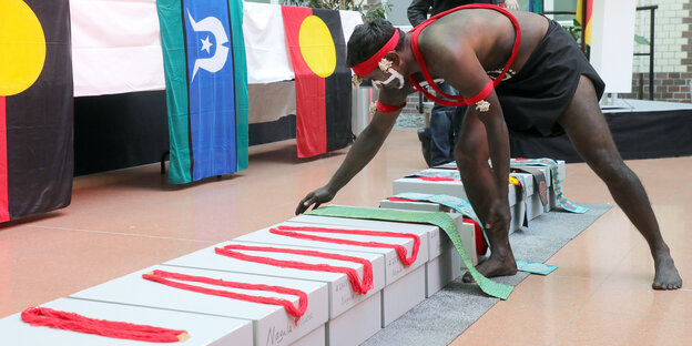 Ein Mann beugt sich über einen Karton mit den sterblichen Überresten der australischen Ureinwohner*innen. Ein Mann beugt sich über einen Karton mit den sterblichen Überresten der australischen Ureinwohner*innen.