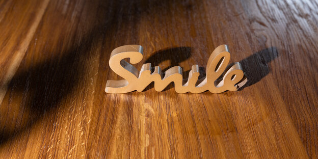 der aus Holz ausgesägte Schriftzug „Smile“ der aus Holz ausgesägte Schriftzug „Smile“