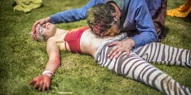 Eine Frau liegt auf dem Boden und wird von einem Mann mit der Nase am Bauch berührt Eine Frau liegt auf dem Boden und wird von einem Mann mit der Nase am Bauch berührt