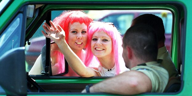 2 Frauen mit roten Perrücken gucken in ein Polizeiauto 2 Frauen mit roten Perrücken gucken in ein Polizeiauto