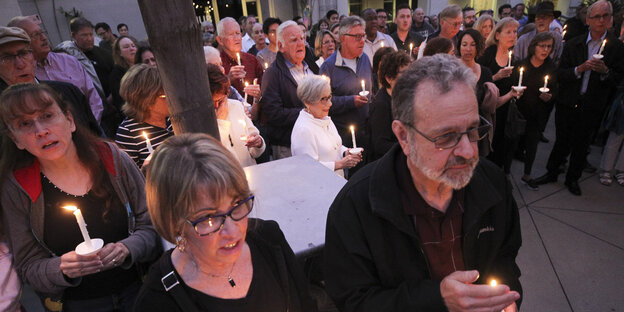 Trauernde Menschen mit Kerzen in einer Kirche Trauernde Menschen mit Kerzen in einer Kirche