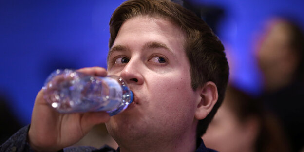 Kevin Kühnert trinkt einen Schluck Wasser bei einer Konferenz Kevin Kühnert trinkt einen Schluck Wasser bei einer Konferenz