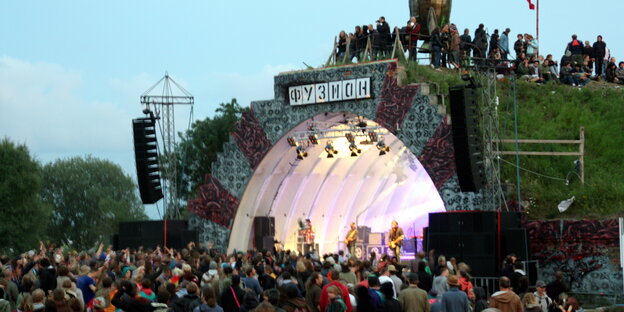 Eine beleuchtete Festivalbühne, davor Zuschauer Eine beleuchtete Festivalbühne, davor Zuschauer