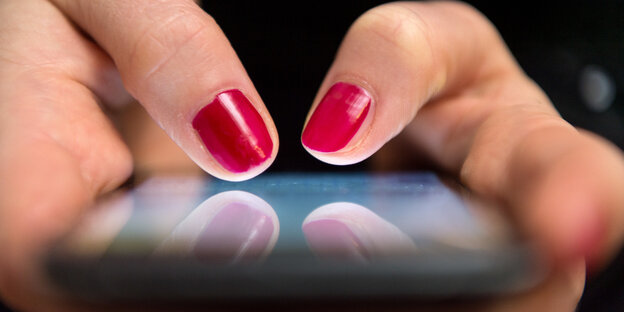 Nahaufnahme eines Smartphone-Displays auf dem jemand mit rot lackierten Fingernägeln tippt. Nahaufnahme eines Smartphone-Displays auf dem jemand mit rot lackierten Fingernägeln tippt.