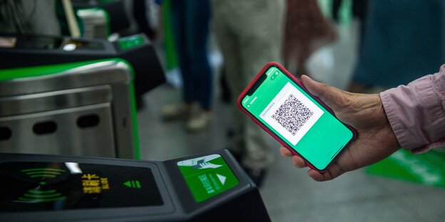 Eine Hand hält ein Smartphone, auf dem ein QR-Code zu sehen ist