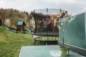 Ein Garten, in dem ein Trampolin und eine Rutschbahn stehen Ein Garten, in dem ein Trampolin und eine Rutschbahn stehen