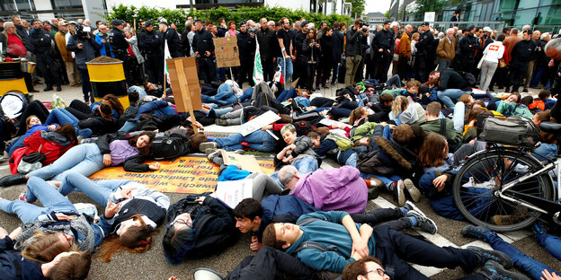 Menschen demonstrieren liegend gegen Bayer Menschen demonstrieren liegend gegen Bayer