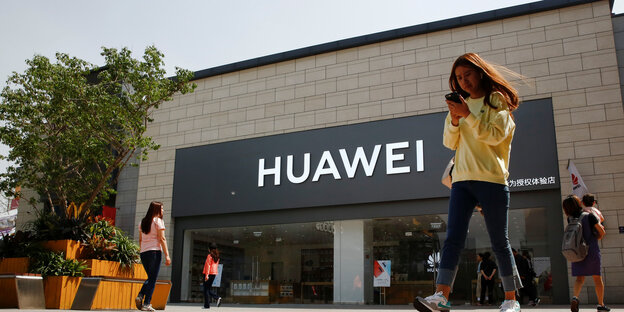 Frau mit Smartphone vor Huawei-Shop Frau mit Smartphone vor Huawei-Shop