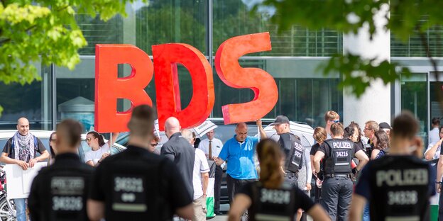 Menshcne halten drei große Buchstaben BDS in die Luft Menshcne halten drei große Buchstaben BDS in die Luft