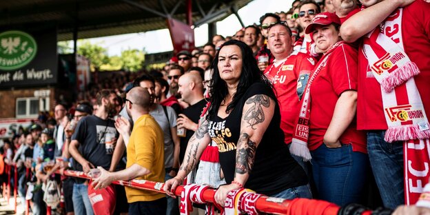 Fußballfans im Stadion, im Zentrum eine Frau mit Tattoos auf den Armen