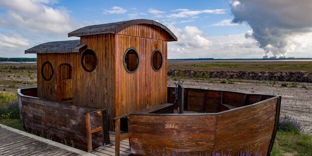 Ein kleines Holzschiff steht symbolisch am Rand des ehemaligen Braunkohletagebaus Cottbus-Nord Ein kleines Holzschiff steht symbolisch am Rand des ehemaligen Braunkohletagebaus Cottbus-Nord