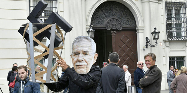 ein Demonstrant mit Van der Bellen-Maske hält einen Papierkorb hoch, in dem ein großes Hakenkreuz steckt ein Demonstrant mit Van der Bellen-Maske hält einen Papierkorb hoch, in dem ein großes Hakenkreuz steckt