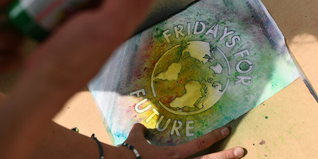 Eine Hand sprüht Farbe auf eine Fridays for Future Schablone Eine Hand sprüht Farbe auf eine Fridays for Future Schablone