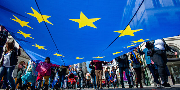 Eine Gruppe trägt eine große EU-Flagge Eine Gruppe trägt eine große EU-Flagge