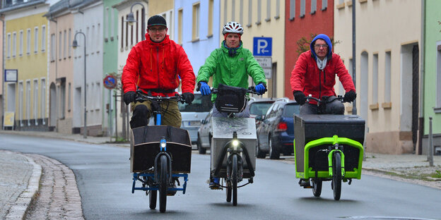 Drei elektrische Lastenfahrräder fahren nebeneinander Drei elektrische Lastenfahrräder fahren nebeneinander