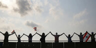 Menschen stehen auf einer Brücke in Beirut halten libanesische Flagge hoch und bilden eine Menschenkette