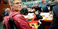 Frau dreht sich zum Fotografen, Stoffkuh in Deutschlandfarben in der Hand