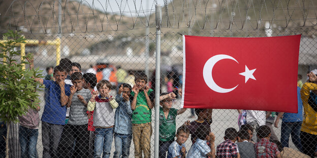 Kinder hinter Stacheldraht, an dem eine türkische Fahne hängt