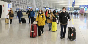 Menschen mit Schutzmasken an einem Flughafenterminal