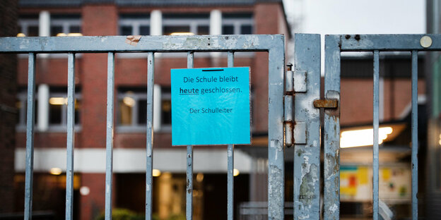 An einem Gitter hängt ein Zettel mit der Aufschrift: "Die Schule bleibt heute geschlossen. Der Schulleiter"