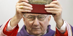Kardinal Pietro Parolin hält eine Bibel hoch