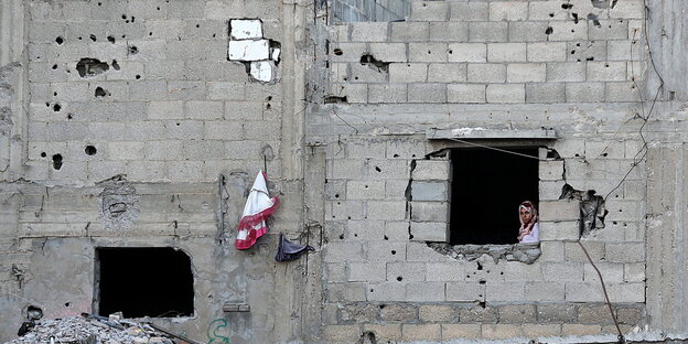 Frau schaut aus einem zerstörten Haus in Gaza-Stadt Frau schaut aus einem zerstörten Haus in Gaza-Stadt