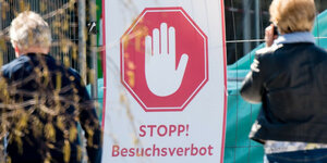 Es ist ein Schild zu sehen, auf dem eine Handfläche abgebildet ist, darunter die Aufschrift "Stopp! Besuchsverbot"