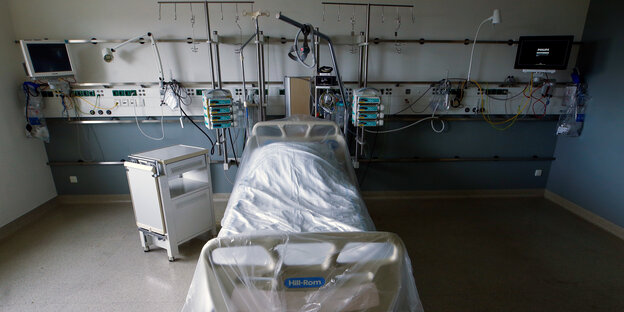 Ein Krankenhausbett auf einer Intensivstation ist mit einer Plastikplane verdeckt