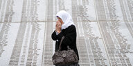 Eine Frau in der Nähe eines Grabes ihrer Familienmitglieder im Gedenkzentrum Potocari