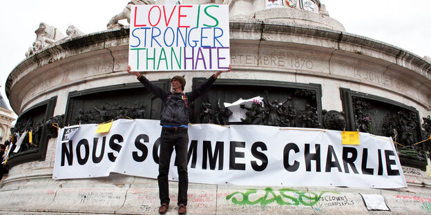 Ein Mann hält ein Plakat auf einer Solidaritätsdemo für Charlie Hebdo