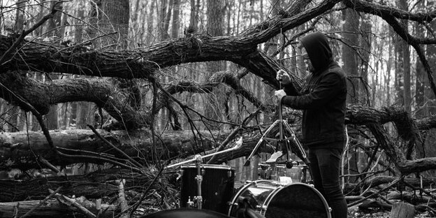 Auf einem schwarzweißen Foto wird ein Schlagzeug im Wald aufgebaut