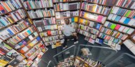 Eine rundgeschwungene bunte Bücherwand, davor eine junges Mädchen