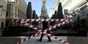 Eine Fußgängerin geht an abgesperrten Bereichen vor Cafés in Wien vorbei