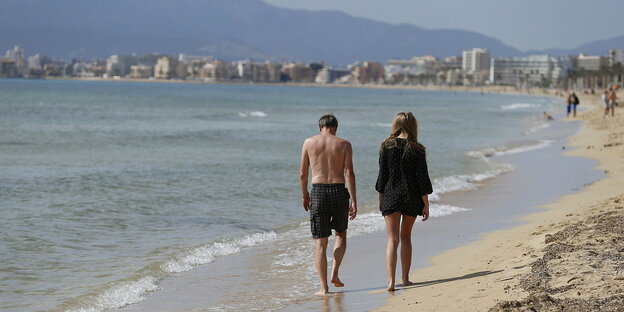 Ein Mann und eine Frau gehen am Strand spazieren