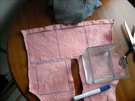 Ein Stück rosa Filz, auf dem Quadrate eingezeichnet sind und eine Schere zum Ausschneiden liegt bereit