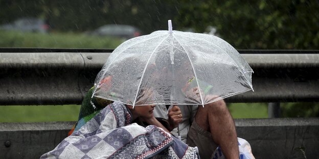 Drei Menschen unter einem Regenschirm Drei Menschen unter einem Regenschirm