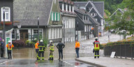 Feuerwehrleute stehen vor einer überschwemmten Straße