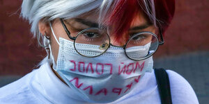 Mensch mit OP-Maske auf der Steht: „Meine Stimme wurde mir gestohlen“