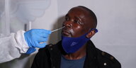 Einem Mann wird ein Teststäbchen in die Nase geschoben.