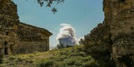 Ein Atommeiler dem Dampf entweicht, im Vordergrund alte Steinhäuser