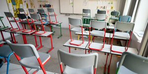 Stühle stehen in einem leeren Klassenzimmer auf den Tischen