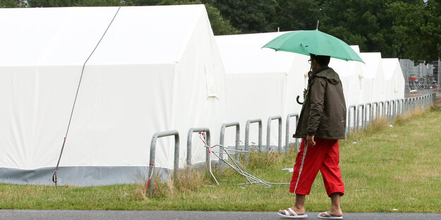 Ein Mann geht an Zeltunterkünften für Flüchtlinge vorbei Ein Mann geht an Zeltunterkünften für Flüchtlinge vorbei