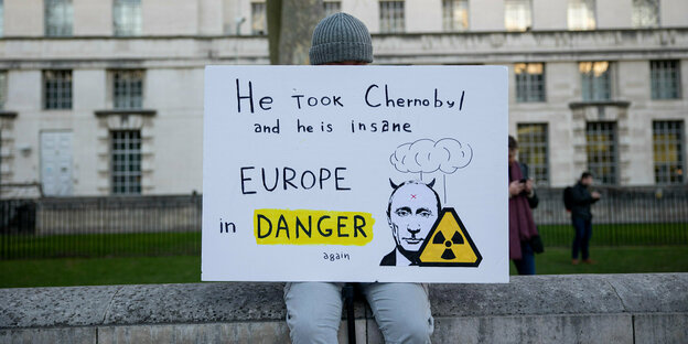 ein Demonstrant trägt ein Schild mit der Aufschrift : " Er hat Tschernobyl eingenommen und er ist wahsinnig. Europa ist in Gefahr."