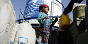 Ein kleiner Junge in Sanaa mit Plastikflasche bei der Ausgabe von Frischwasser