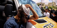 Ein junger Mann mit Kippa und orthodoxen Locken senkt trauernd den Kopf neben einem israelischen Rettungswagen