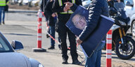 Mann auf dem Tesla-Gelände hält Poster von Elon Musk