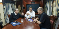 Macron, Draghi und Scholz sitzen in einem Zug an einem Holztisch in Richtung Kiew