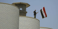 Mann mit irakischer Fahne auf dem Dach des irakischen Parlamentsgebäudes
